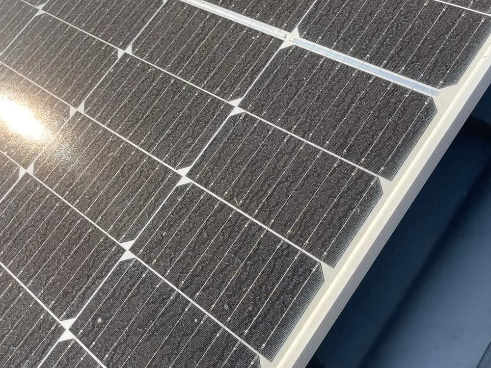 Dust-covered solar panels on a tiled residential roof before cleaning