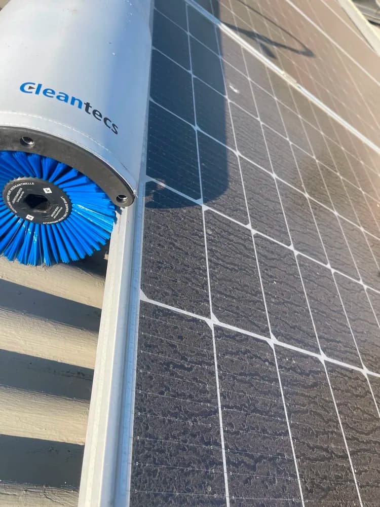 Heavily soiled solar panels beside a Cleantecs cleaning brush before the pass