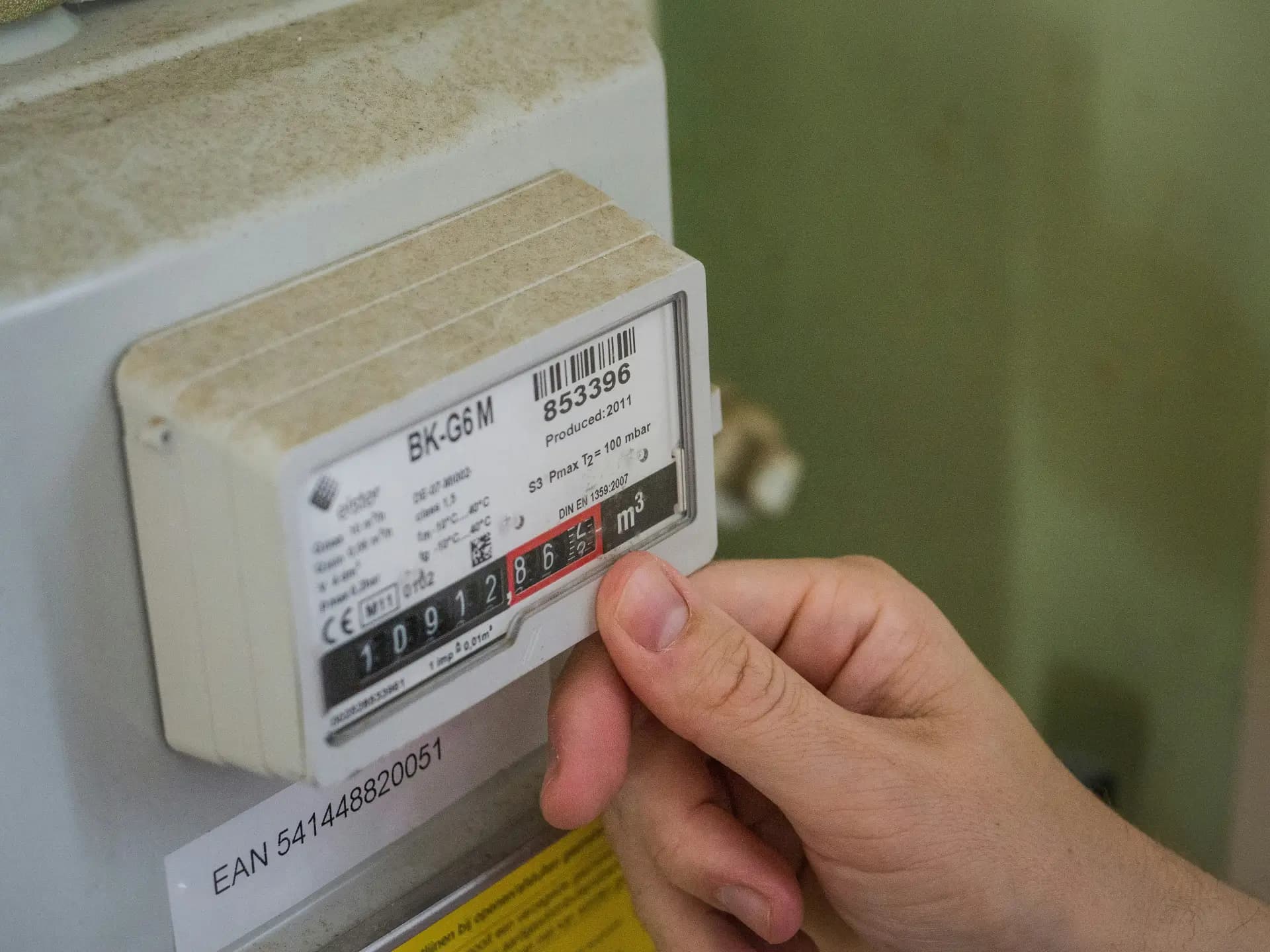 Hand pointing at a residential utility meter reading, illustrating rising electricity costs